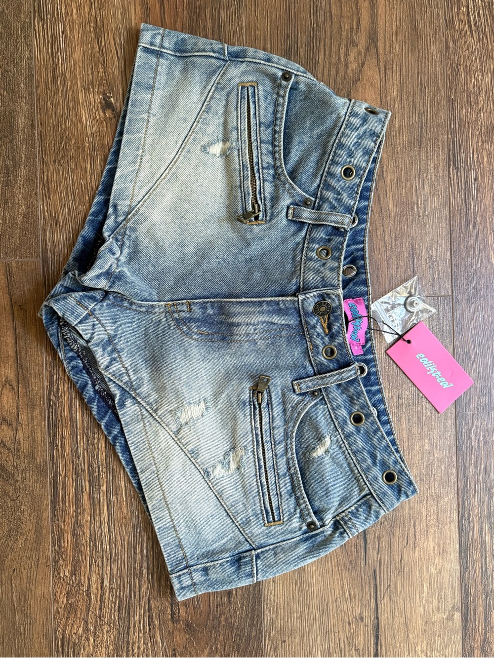 Edikted Tulie Grommet
Distressed Denim Shorts in a blue-washed color